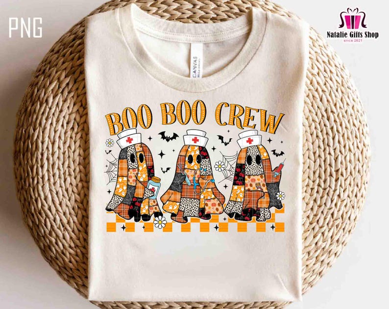 K&ouml;nnte beinhalten: Cremefarbenes T-Shirt mit dem Text "BOO BOO CREW" in Orange. Das Design zeigt drei Geisterfiguren in Patchworkmustern, die Krankenschwesternh&uuml;te tragen und medizinische Gegenst&auml;nde halten. Flederm&auml;use, Spinnweben und Blumen vervollst&auml;ndigen das Halloween-Thema.