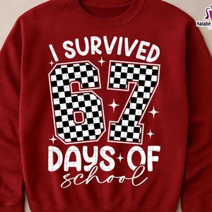 May include: A maroon sweatshirt with the text "I SURVIVED 67 DAYS OF school" in white. The numbers "67" are designed with a black and white checkered pattern. The sweatshirt also has star accents.