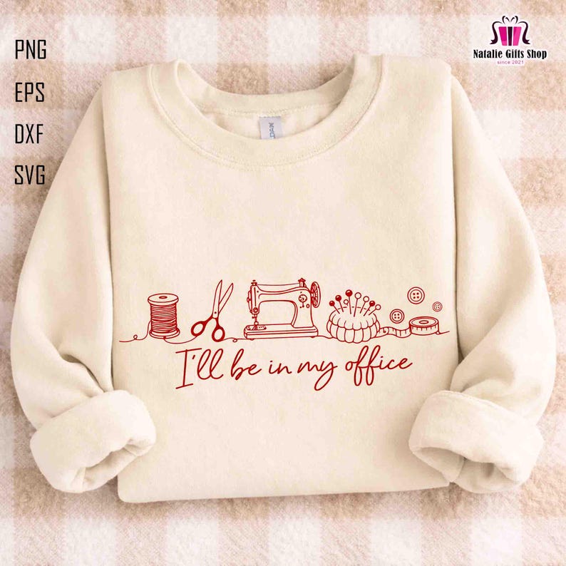 May include: Cream-colored sweatshirt with red line art of sewing tools: thread spool, scissors, sewing machine, pincushion, buttons, and measuring tape. The text "I'll be in my office" is below the graphic. The sweatshirt has a crew neck and long sleeves.