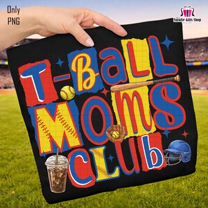 May include: Black t-shirt with a colorful graphic that reads "T-Ball Moms Club." The design includes baseballs, a bat, a glove, and a baseball helmet. A cold drink with ice is also featured in the design.