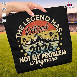Puede incluir: Camiseta negra con un diseño retro. El diseño incluye el texto "THE LEGEND HAS Retired 2026 NOT MY PROBLEM Anymore" en un diseño circular con una montaña, palmeras y un fondo de puesta de sol.