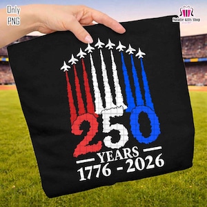 May include: Black tote bag featuring a patriotic design with the text "250 YEARS 1776-2026". The design includes red, white, and blue jets with vapor trails. The bag is held against a backdrop of green grass and a stadium.
