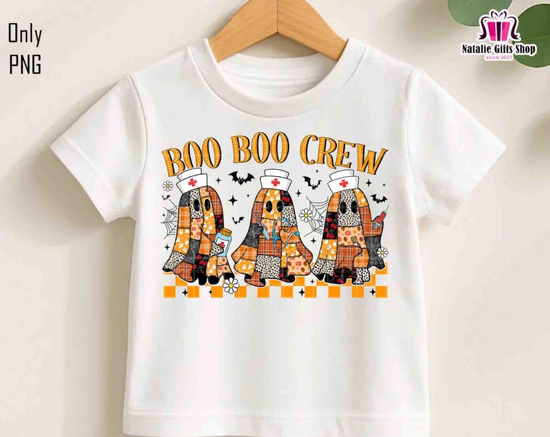 K&ouml;nnte beinhalten: Wei&szlig;es T-Shirt mit dem orangefarbenen Text "BOO BOO CREW". Das Design zeigt drei Geisterfiguren in Patchwork-Mustern, die Krankenschwesternh&uuml;te tragen und medizinische Gegenst&auml;nde halten. Flederm&auml;use und Spinnweben vervollst&auml;ndigen das Halloween-Thema.
