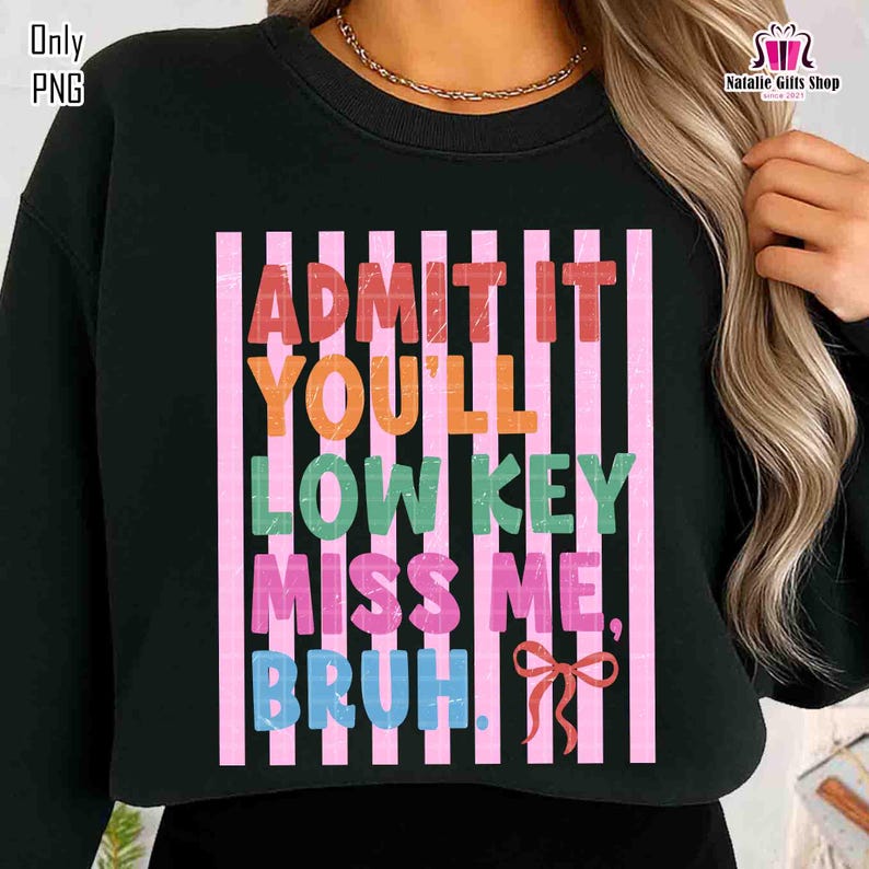 May include: Black sweatshirt with the text "ADMIT IT YOU'LL LOW KEY MISS ME, BRUH" in colorful letters. The text is set against a background of pink and white vertical stripes, with a small pink bow at the bottom.