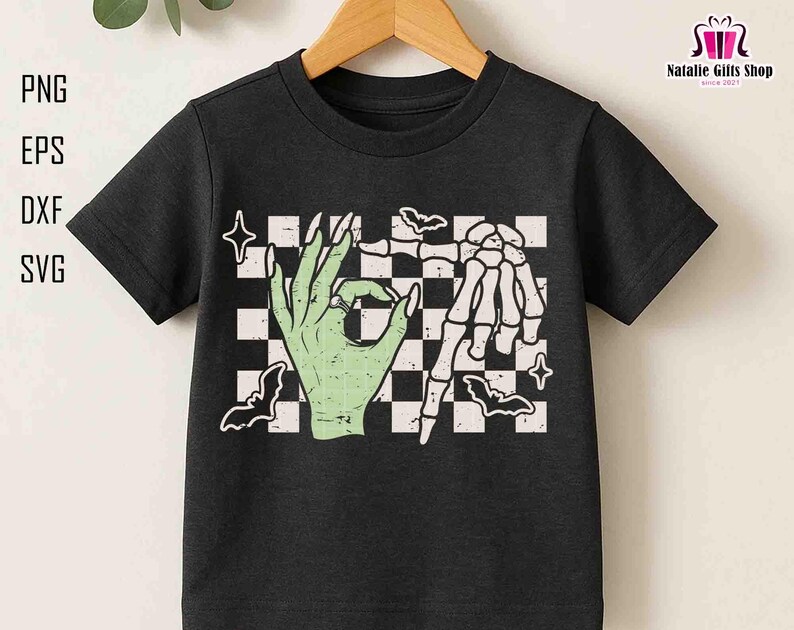 May include: Black t-shirt featuring a green hand making an 'okay' gesture and a skeleton hand, set against a checkered background with bats and stars. The shirt has the text 'PNG, EPS, DXF, SVG' on the left side.