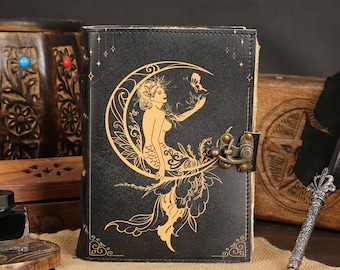 Può includere: Un diario in pelle nera con un design in rilievo dorato di una sirena seduta su una luna crescente. Il diario ha una chiusura a scatto in metallo.