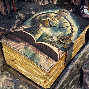 May include: A leather-bound journal with a vintage clock and open book design. The journal has a brass clasp and a black leather strap. The pages are made of aged paper.