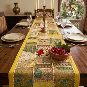 May include: A rectangular table runner featuring a patchwork design of embroidered fabric squares in yellow, gold, green, and blue. The runner is decorated with intricate beadwork, floral patterns, and sequins, finished with a solid yellow border.