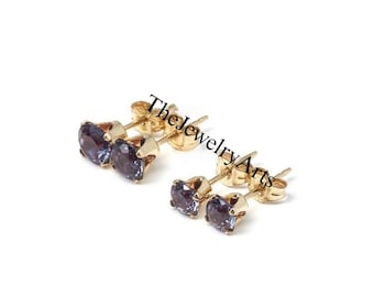 Peut inclure: Une paire de boucles d'oreilles en or avec deux pierres précieuses violettes dans chaque boucle d'oreille. Les boucles d'oreilles sont de style simple et classique.