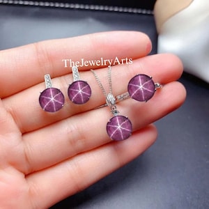 以下が含まれることがあります： 星形ルビーのペンダント、イヤリング、リングがセットになったジュエリー。ジュエリーはスターリングシルバー製で、6つのポイントを持つ星形ルビーの宝石が特徴です。