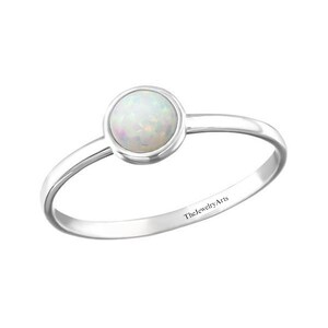May include: A silver ring with a white opal gemstone. The ring is inscribed with "TheJewelryArts".
