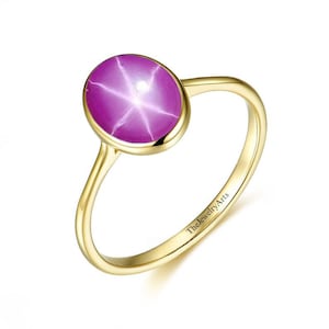 May include: A gold ring with a pink star sapphire gemstone. The ring is engraved with "TheJewelryArts".