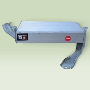 May include: A silver rectangular automotive amplifier unit with integrated metal mounting brackets on both sides. The front face features a black label with the text 86280-0W240, JBL, and Harman/Becker USA, alongside a small red circular sticker labelled CHECK.