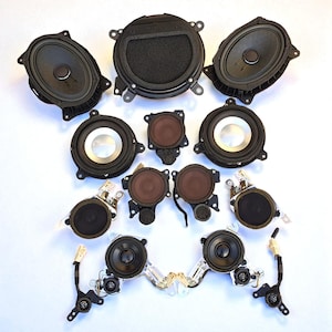 Puede incluir: Una colección de doce altavoces de audio para automóviles en color negro, con diversas formas y tamaños, incluyendo unidades ovaladas y circulares. Algunos altavoces cuentan con anillos metálicos plateados, soportes de montaje y cableado.