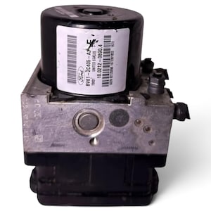 Op de afbeelding: Een zwarte en metallic zilveren ABS-hydraulische regeleenheid voor auto's met een cilindrische motorbehuizing en een wit label met het Ford-logo, onderdeelnummer BV61-2C405-AJ, en diverse barcodes en serienummers op het oppervlak.