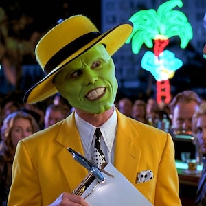 Puede incluir: Un personaje que lleva un sombrero fedora amarillo brillante con una banda negra y una chaqueta de traje amarilla a juego sobre una camisa blanca de cuello con una corbata de lunares blancos y negros. La cara está pintada de verde brillante.