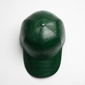 May include: A dark green baseball cap with a textured, crocodile-like pattern. The cap has a curved brim and a button on top. The hat is made of a solid, dark green material.