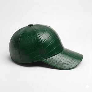 May include: A dark green baseball cap with a textured, crocodile-skin pattern. The cap has a curved brim and a button on top. The hat is made of a shiny material and is set against a white background.