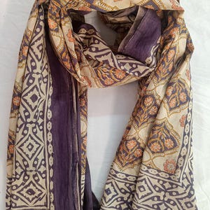 Close-up detail of a handmade block print pareo showing the intricate wooden stamp textures and soft weave of high-quality organic cotton fabric in a bohemian botanical design.