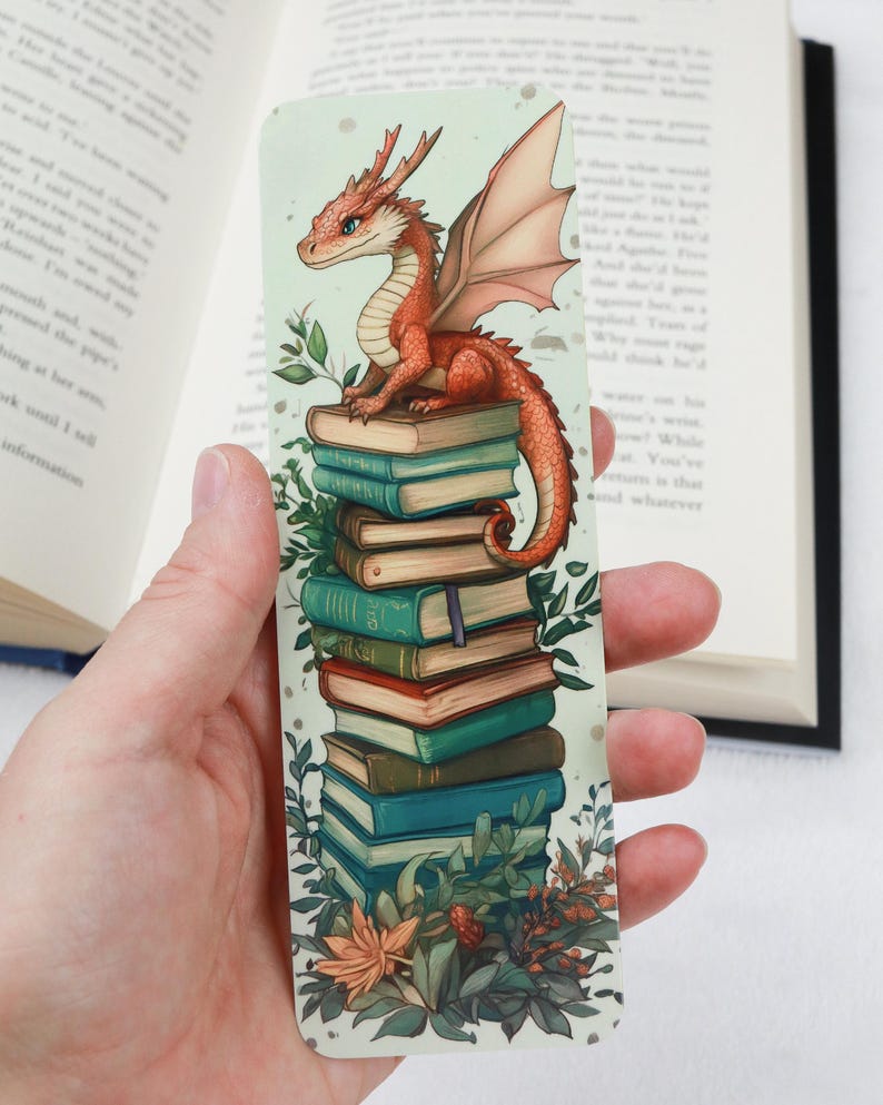 May include: A whimsical bookmark featuring a red dragon perched atop a stack of books. The dragon has detailed wings and a friendly expression. The books are in shades of blue, green, and brown, with botanical accents around the edges. A unique accessory for book lovers.