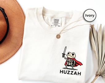 Camiseta con bolsillo de rana "Huzzah", colores cómodos, camiseta de caballero medieval caprichoso, camiseta renacentista con esqueleto de caballero rana, camiseta humorística "Huzzah"