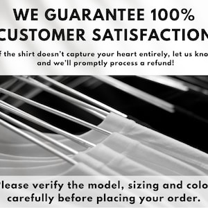 May include: White t-shirts hanging on metal hangers, with text that reads "WE GUARANTEE 100% CUSTOMER SATISFACTION" and "Please verify the model, sizing and color carefully before placing your order."