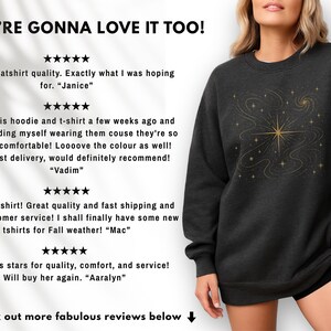 May include: Dark gray sweatshirt with a gold celestial design. The design features a central starburst with swirling lines and smaller stars. The text "YOU'RE GONNA LOVE IT TOO!" is at the top of the image.