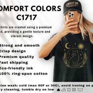 May include: Black t-shirt with a gold cat design, moon, and sun graphic. The shirt has the text "COMFORT COLORS C1717". The shirt is made of 100% ring-spun cotton.