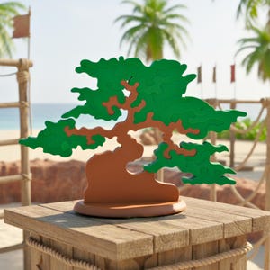 May include: A wooden bonsai tree puzzle with green leaves and a brown trunk and base. The puzzle is displayed on a wooden table with a beach scene in the background. The puzzle is a decorative item.