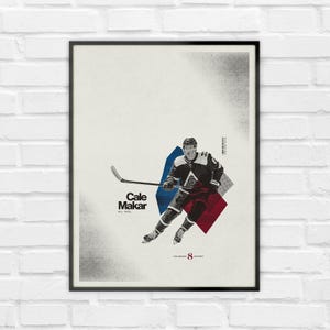 Könnte beinhalten: Ein gerahmtes Poster mit einer grafischen Illustration des Eishockeyspielers Cale Makar im dunklen Trikot mit Hockeyschläger. Das Design enthält blaue und rote geometrische Formen sowie den Text Cale Makar, All Hail und Colorado 8 Hockey.