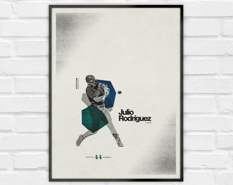 May include: A framed vertical poster featuring a graphic illustration of a baseball player swinging a bat. The design includes the text Julio Rodriguez, Seattle 44 Baseball, and Mariners, with geometric blue and teal shapes on a light background.