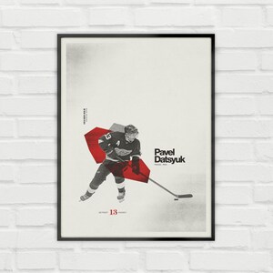 Könnte beinhalten: Gerahmtes Poster mit einem Eishockeyspieler im Trikot der Detroit Red Wings, Nummer 13. Das Poster hat ein minimalistisches Design mit einer roten geometrischen Form und dem Namen des Spielers, Pavel Datsyuk, in fetter Schrift. Der Hintergrund ist neutral.