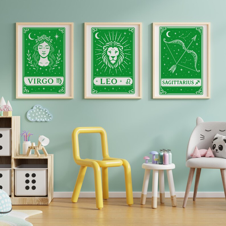 May include: Three green framed prints with white zodiac signs. The signs are Virgo, Leo, and Sagittarius. The prints are hanging on a light blue wall.