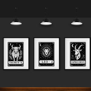May include: Three black and white framed prints with zodiac signs. The first print features a bull with the text "Taurus ♉". The second print features a lion with the text "LEO ♌". The third print features a goat with the text "CAPRICORN ♑".