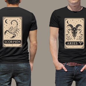 May include: Two black t-shirts with zodiac signs printed on the front. The left shirt features a scorpion with the text "SCORPIO" and the right shirt features a ram with the text "ARIES".