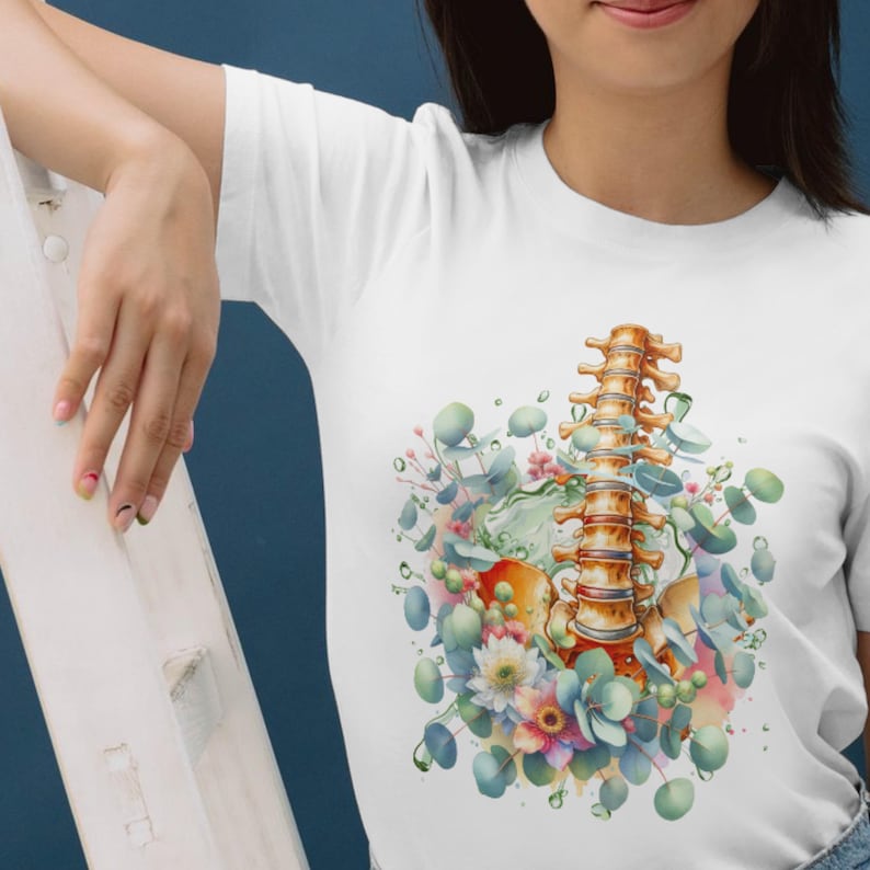 May include: White t-shirt featuring a watercolor illustration of a spine with floral and eucalyptus accents. The design includes a detailed depiction of the vertebrae, surrounded by soft pastel colors and green foliage.
