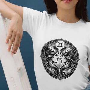 May include: White t-shirt with a black and white illustration of the Gemini zodiac sign. The illustration features two women facing each other with their heads touching. The sign "II" is above their heads.