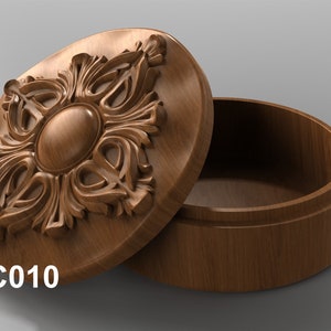 May include: A wooden box with an intricate carved design on the lid. The box is open and the inside is empty. The box is labeled "JC010".