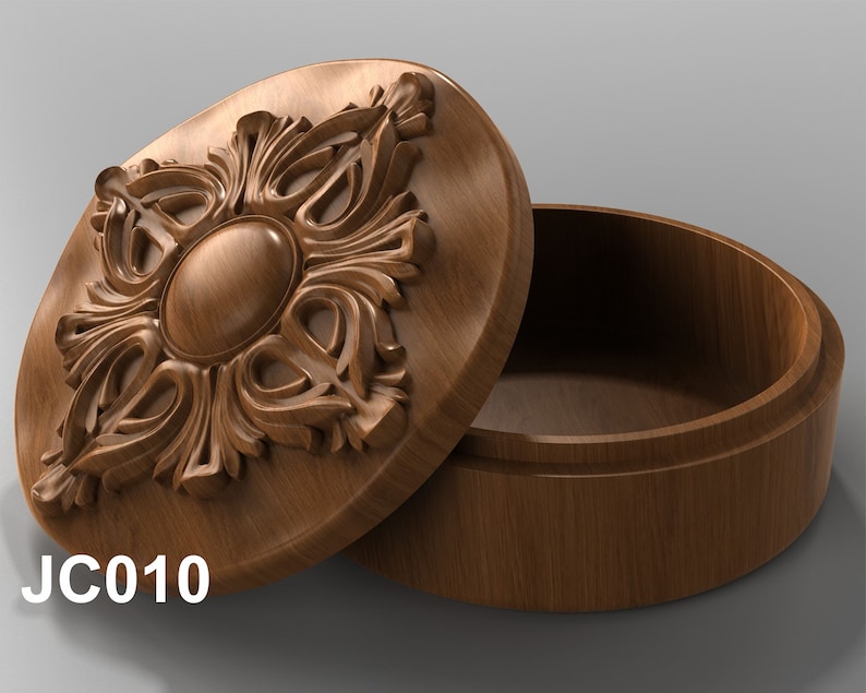 May include: A wooden box with an intricate carved design on the lid. The box is open and the inside is empty. The box is labeled "JC010".