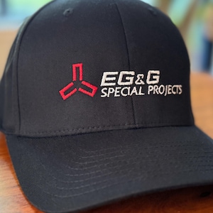 May include: Black baseball cap with a red and white logo that says "EG&G SPECIAL PROJECTS".