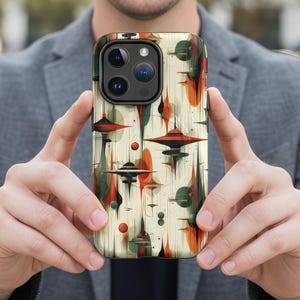 May include: A phone case with a mid-century modern design. The case features a cream-colored background with abstract shapes in red, orange, green, and black. The design includes geometric forms and stylized elements reminiscent of the atomic age.