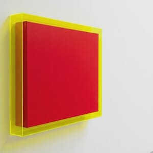 Puede incluir: Una obra de arte moderna con un cuadrado rojo vibrante encerrado en un marco de acrílico amarillo neón. La obra está montada en una pared blanca, creando un contraste llamativo de colores y formas.
