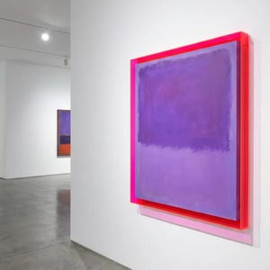 Op de afbeelding: Een galerij met abstracte schilderijen. Het belangrijkste kunstwerk is een groot, rechthoekig stuk met een verloop van paarse tinten, omlijst door een levendige roze en rode rand. Andere schilderijen met vergelijkbare kleurenpaletten zijn zichtbaar op de achtergrond.