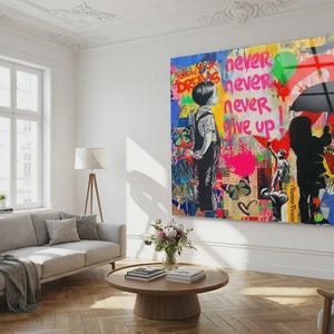 May include: A large, colorful wall art piece with the words "never never never give up" in pink and white. The artwork features two figures, one with an umbrella, and graffiti-style elements.