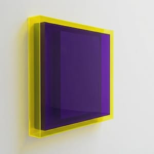 May include: A modern art piece featuring a rectangular, layered design. The artwork has a vibrant yellow frame, surrounding a deep purple interior. The piece is mounted on a white wall, creating a striking contrast.