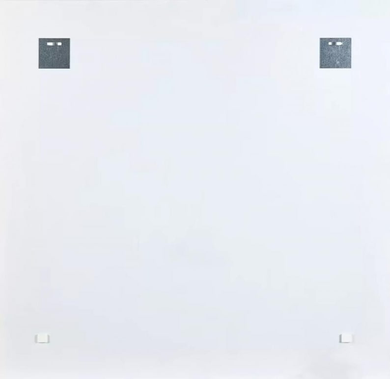 May include: A white background with two dark gray square shapes at the top and two smaller shapes at the bottom. The square shapes at the top have two small, horizontal, rectangular cutouts. The smaller shapes at the bottom are rectangular.