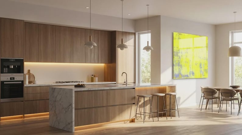 May include: Modern kitchen with wooden cabinetry, a marble-topped island, and pendant lights. Features a built-in oven and microwave, a dining area with chairs, and a large abstract painting with yellow and blue tones.