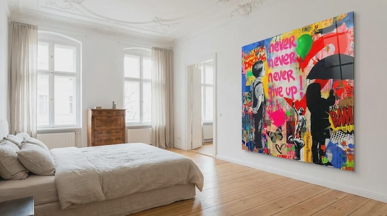 May include: A large, colorful Banksy-style artwork with the words "Never, Never, Never Give Up" dominates a bedroom wall. The artwork features silhouetted figures, graffiti-style elements, and vibrant colors, creating a bold statement piece.