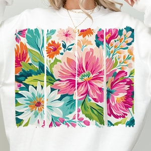 May include: White sweatshirt with a colorful floral print. The print features pink, red, orange, yellow, green, and blue flowers.