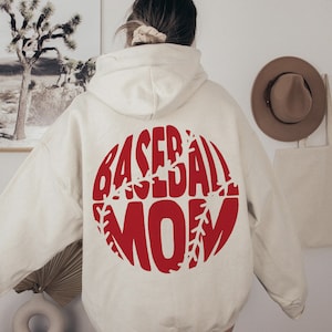 May include: A cream-colored hoodie with a red baseball graphic that says "Baseball Mom" on the back.